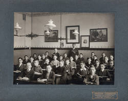 Gruppenbildnis einer Jungenklasse im Klassenraum mit Lehrer;