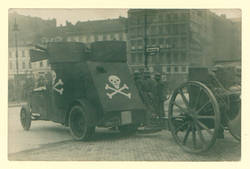 Regierungstruppen hinter einem Panzerauto mit Totenschädel und einer Haubitze