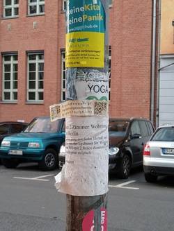 diverse Anschläge und Sticker an einem Straßenschild in Prenzlauer Berg;