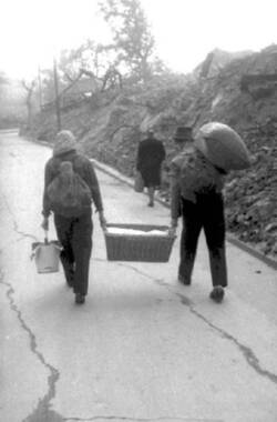 "Hamsterndes" Paar mit Wäschekorb, Eimer und Rucksack auf dem Weg durch das zerstörte Berlin