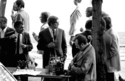 o.T.,  Schlange Stehende und Bier trinkende Menschen an einem Imbiss-Kiosk, auf dem Tisch Brause-, Bier- und Schnaps-Flaschen