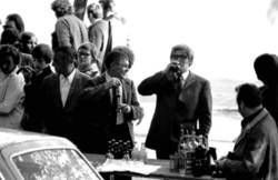 o.T.,  Schlange Stehende und Bier trinkende Menschen an einem Imbiss-Kiosk, auf dem Tisch Brause-, Bier- und Schnaps-Flaschen