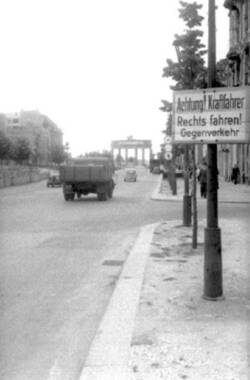 Straßenschild "Achtung Kraftfahrer. Rechts fahren! Gegenverkehr". Im Hintergrund das Brandenburger Tor