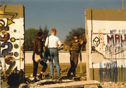 Grenzsoldat im Gespräch mit zwei Personen an der geöffneten Berliner Mauer