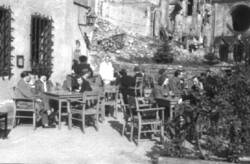 Menschen sitzen an Terrassentischen vor einem Lokal in der Sonne . Im Hintergrund die Ruine der Kaiser-Wilhelm-Gedächtniskirche