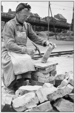 Trümmerfrau mit Putzhammer beim Säubern der Steine ("Steine klopfen")