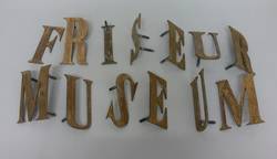Metallbuchstaben von der Außenwand des Friseurmuseums;