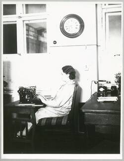 Junge Frau, an der Schreibmaschine sitzend