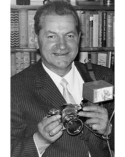Herbert Maschke mit Kamera vor einem Bücherregal
