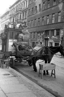Ein Pferd zieht einen Waagen mit Möbeln auf der Straße.