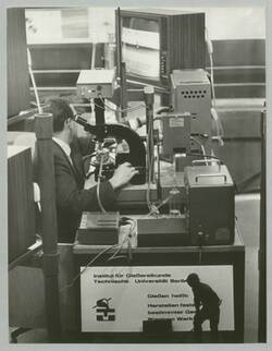 "Gießversuch (Gußeisen) wird über Mikroskop und Fernsehkamera aufgenommen". Industrieausstellung Berlin 1968