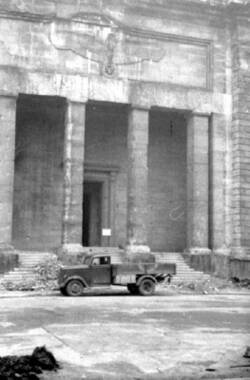 Ein Pritschenwagen steht vor dem Eingangsportal der zerstörten Reichskanzlei
