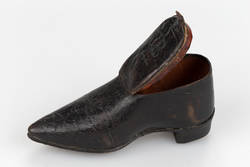 Dose in Schuhform mit Spielwürfeln im Absatz;