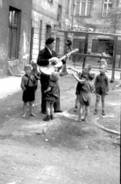 Gitarrenspieler begeistert Kinder auf einen Hof mit seiner Musik.