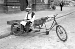 Mann sitzt Zeitung lesend auf einem Transport-Dreirad am Anhalter Bahnhof