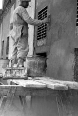 Wiederaufbau. Ein Maurer auf einem Grüst verputzt eine Wand