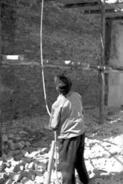 Wiederaufbau. Ein Arbeiter hält ein von einem Baugerüst hängendes Seil
