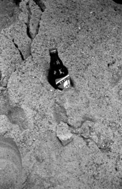 o.T., In einem Sandhaufen abgestellte Bierflasche