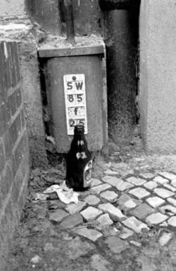 o.T., An einer Haus-Ecke abgestellte Bierflasche