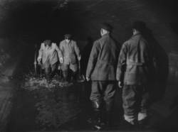 Unter den Straßen von Berlin. Tunnel mit vier Arbeitern im Wasser stehend