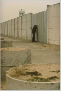 o.T., Männliche Person späht durch ein Tor in der Hinterlandmauer, im Hintergrund ein Beobachtungsturm