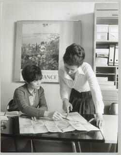 o.T., Zwei Frauen beugen sich am Schreibtisch über eine Landkarte
