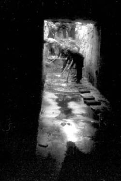 Frauen und Männer schaufeln Sand in einen unter Wasser stehenden Kellergang