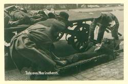 "Tote aus Marinehaus."; drei Männer bahren einen Toten auf; im Hintergrund drei weitere Leichname auf einem Wagen