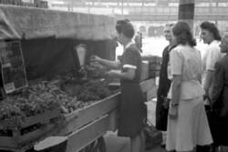 Frau wiegt Gemüse an einem Marktstand ab