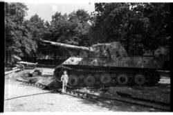 Junge mit Roller vor dem Wrack eines deutschen Panzers