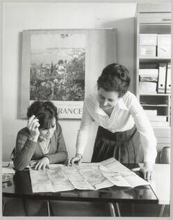o.T., Zwei Frauen beugen sich am Schreibtisch über eine Landkarte
