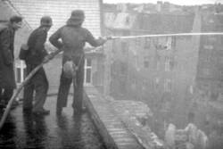 Propangasexplosion in Berlin-Charlottenburg. Mit Wasser löschende Feuerwehrmänner auf einem Hausdach