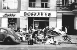 o.T., Straßenszene: Passanten bei einem Müll-Haufen vor einem Tabekwaren- und Lotto-Laden und der Kneipe "Destille"