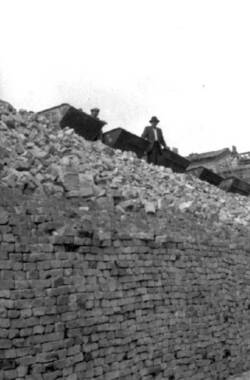 Zwei Männer stehen an einem Lorenzug auf einem Trümmerwall