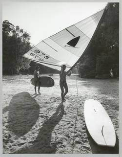 o.T., Zwei junge Männer tragen Surfboard und Segel. Wannseestrand