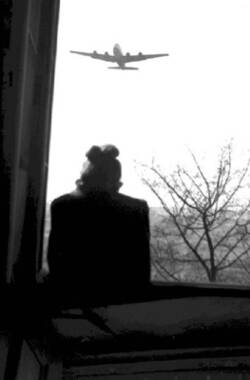 Luftbrücke. Frau schaut in Richtung eines am Himmel nahenden Transportflugzeugs