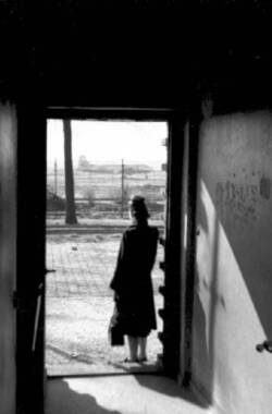 Luftbrücke. Frau steht im Gegenlicht in einer Türöffnung. Im Hintergrund der Flughafen Tempelhof