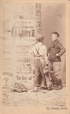 Zwei Jungen vor einer Litfaßsäule mit einer Anzeige anlässlich der Neueröffnung des Fotoateliers von Theodor Prümm