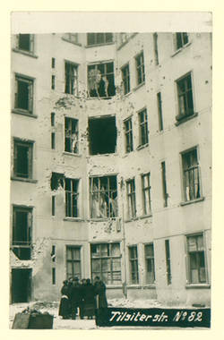 "Tilsiterstraße N° 82"; Gruppe v. Personen vor zerstörten Fassaden im Hinterhof
