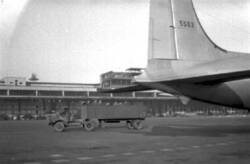 Luftbrücke. LKW auf dem Rollfeld des Flughafens Tempelhof. Rechts ein Leitwerk