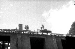 Schornstein mauernder Bauarbeiter auf dem Dach eines Rohbaus