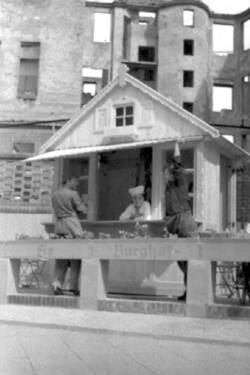Hölzerne Eisverkaufshütte mit Terrasse. Im Hintergrund Ruinen