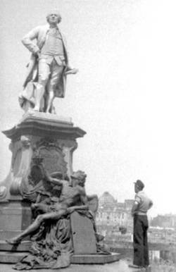 Mann stehend vor dem Lessing-Denkmal, im Hintergrund das Reichstagsgebäude