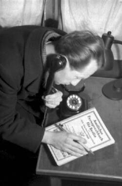 Telefonierender Mann, vor sich auf dem Tisch ein Telefonbuch