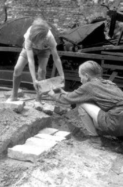 Zwei Jungen legen ein Fundament beim Hausbau-Spiel zwischen Ruinen