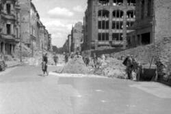 Trümmerfrauen in einer von Ruinen gesäumten Straße
