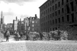 Trümmerbeseitigung in einer von Ruinen gesäumten Straße. Im Hintergrund die Petrikirche