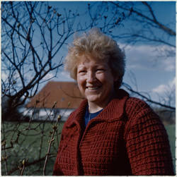 "Landwirtschaft" / Portrait einer Frau, im Hintergrund ein Haus und Landschaft