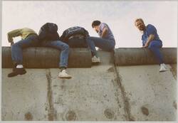 o.T., Junge Männer sitzen auf der Berliner Mauer